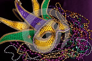 Mardi gras mask and beads on a purple background