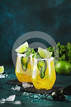 Margarita cocktail with tequila, mango juice, jalapeno pepper, lime and salt, blue background