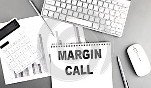 MARGIN CALL text written on notebook on grey background with chart and keyboard , business concept