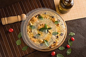 Marguerita pizza with top view, decorated with basil, cherry tomatoes and black olives