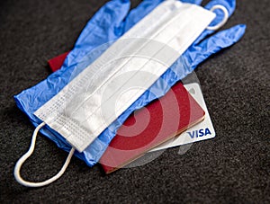 Mari El, Russia - May 10, 2021: Credit visa card, document with blue glove and white mask. Dark background