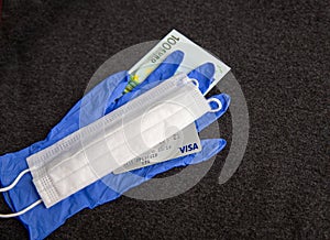 Mari El, Russia - May 10, 2021: Credit visa card, euro. Blue latex glove and white mask. Dark background