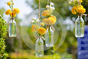 The marigold flowers in a glass bottle hanging