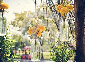 The marigold flowers in a glass bottle hanging