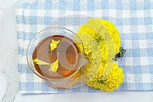 Marigold herbal tea in a glass cup fresh flowers on sackcloth