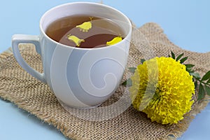 Marigold herbal tea in a glass cup fresh flowers on sackcloth