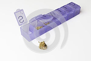 Marijuana buds in drugs container on white from side