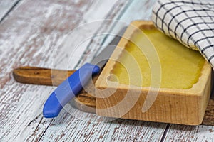 Marijuana butter with wooden mould on blue old table with checker dish towel