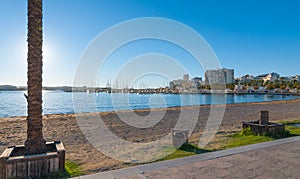 Marina & bay in St Antoni de Portmany, Ibiza, Balearic Islands, Spain. Calm water along boardwalk & beach in warm, late day sun