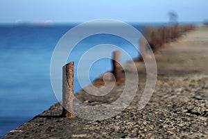 Marina bollard bitt at jetty for boats, ships and yachts mooring. Old broken rusty metal sticks on a pier