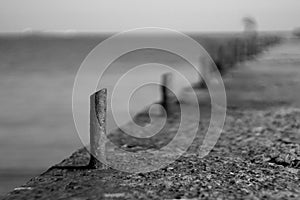 Marina bollard bitt at jetty for boats, ships and yachts mooring. Old broken rusty metal sticks on a pier. Black and White