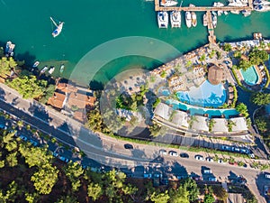 Marina and pier with yachts, seaside town on the beach, hotel and swimming pools.