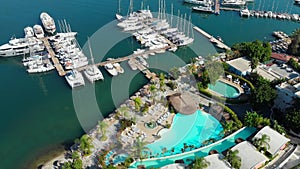 Marina and pier with yachts, seaside town on the beach, hotel and swimming pools.