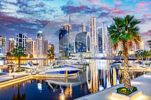 Marina with yachts and skyscrapers in Dubai UAE with Burj Khalifa at night