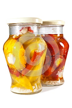 Marinaded tomatoes, stuffed and bush pumpkins and vegetable marrows in glass jar on a white background