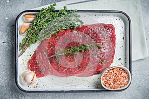 Marinatad flank beef steak with herbs and olive oil, raw meat. Gray background. Top view