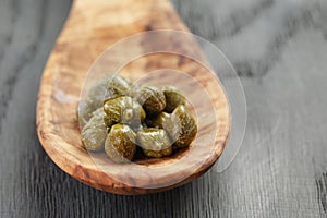 Marinated capers in wood spoon on table