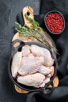 Marinated chicken wings with spices and herbs in a pan. Black background. Top view