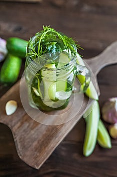 Marinated cucumbers gherkins. Pickles with mustard and garlic. Glass jar with fermented cucumbers on grey table. Pickled cucumbers