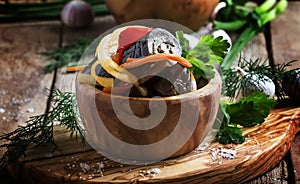 Marinated eggplant with onions and peppers in a bowl, vintage wooden background, selective focus