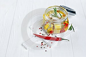 Marinated feta cheese with olive oil and spice of red chili pepper and rosemary in glass jar