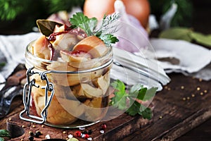 Marinated forest white mushrooms boletus in glass jar with spices and herbs, ready to eat, cooking food or canning concept, wooden