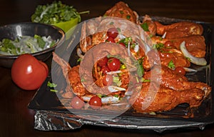 Marinated and garnished uncooked tandoori style chicken