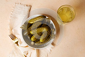 Marinated gherkins in a bowl and pickled juice or cucumber pickle