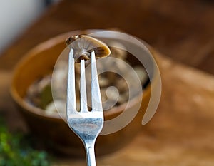 Marinated honey fungus in brown bowl on wooden table.