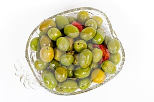 Marinated olives in small transparent bowl. On white background. Pickled green olives