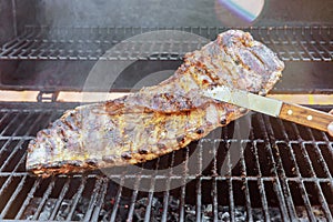 Marinated pork ribs are being roasted in BBQ hot a flaming grill