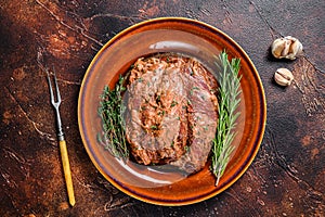 Marinated skirt bavette steaks in bbq sauce on a plata. Dark background. Top view