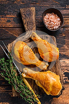 Marinated and Smoked chicken legs drumsticks on a wooden cutting board. Dark wooden background. Top view