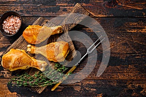 Marinated and Smoked chicken legs drumsticks on a wooden cutting board. Dark wooden background. Top view. Copy space