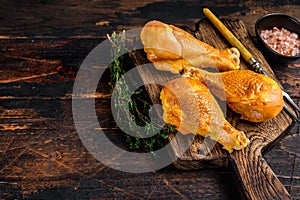 Marinated and Smoked chicken legs drumsticks on a wooden cutting board. Dark wooden background. Top view. Copy space