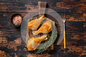 Marinated and Smoked chicken legs drumsticks on a wooden cutting board. Dark wooden background. Top view