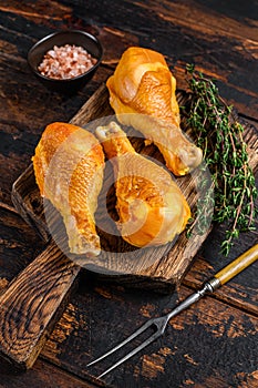 Marinated and Smoked chicken legs drumsticks on a wooden cutting board. Dark wooden background. Top view