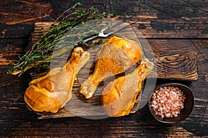 Marinated and Smoked chicken legs drumsticks on a wooden cutting board. Dark wooden background. Top view