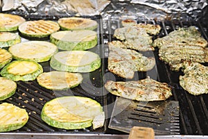 Marinated turkey steaks and zucchini medallions cooking on grill