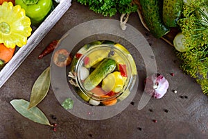 Marinated vegetables in a glass jar. Assorted cucumbers, peppers, carrots, patissons, zucchini.