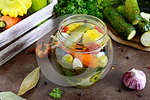 Marinated vegetables in a glass jar. Assorted cucumbers, peppers, carrots, patissons, zucchini.