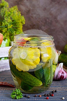 Marinated vegetables in a glass jar. Assorted cucumbers, peppers, carrots, patissons, zucchini.