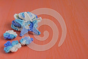 Marine background with cotton lace crochet craft elements: stars, shells, flowers made of soft acrylic like wool yarn. Crocheted c