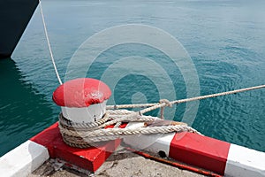 Marine bollard and old rope on pier used and footpath color red and white no parking in the area in this area