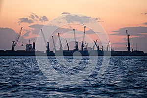Marine cargo port with cranes at sunset