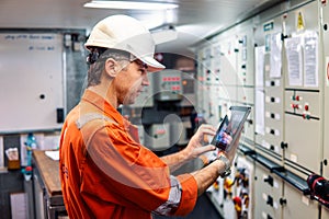 Marine chief engineer watching digital tablet in engine control room