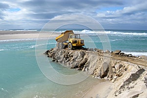 Marine construction. truck dumping rocks at sea