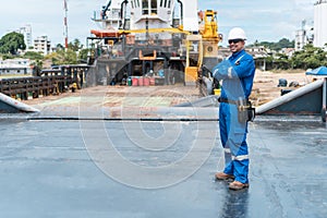 Marine deck officer or chief officer on deck of ship or seagoing vessel, with PPE personal protective equipment - hull, covered photo