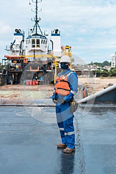 Marine deck officer with protective mask on seagoing vessel, with personal protective equipment photo