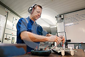 Marine electrical engineer officer in engine control room ECR. He works in workshop